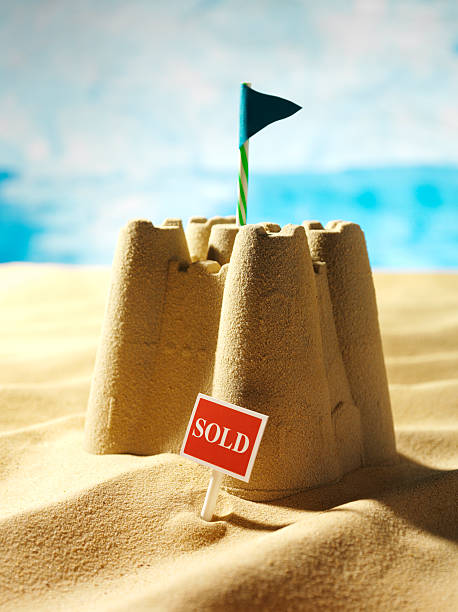 sandcastle on sunny day with "sold" sign out front